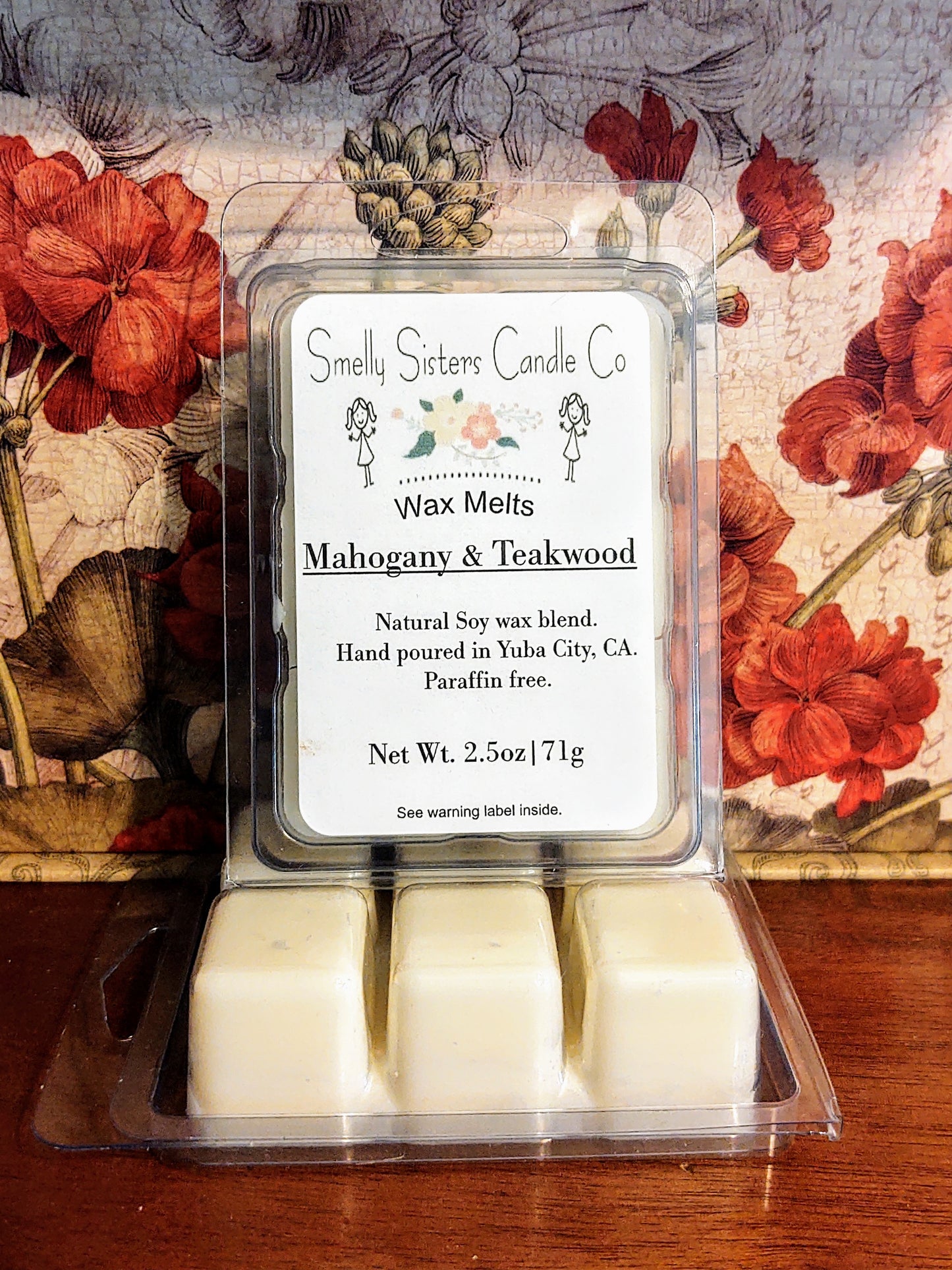 A clear plastic clamshell packaging containing Dye free mahogany and teakwood soy wax melts. Paraffin free, phthalate free, cleaner burning.
