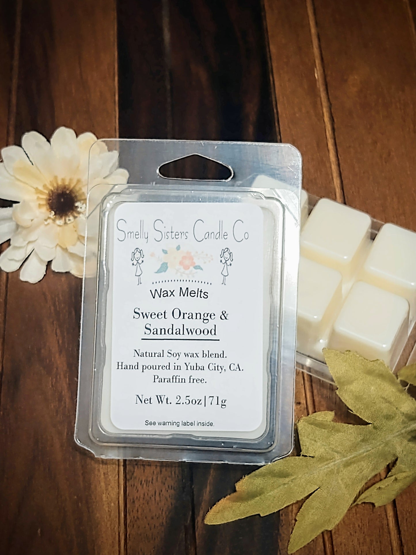 A clear plastic clamshell packaging containing Dye free sweet orange and sandalwood soy wax melts. Paraffin free, phthalate free, cleaner burning.